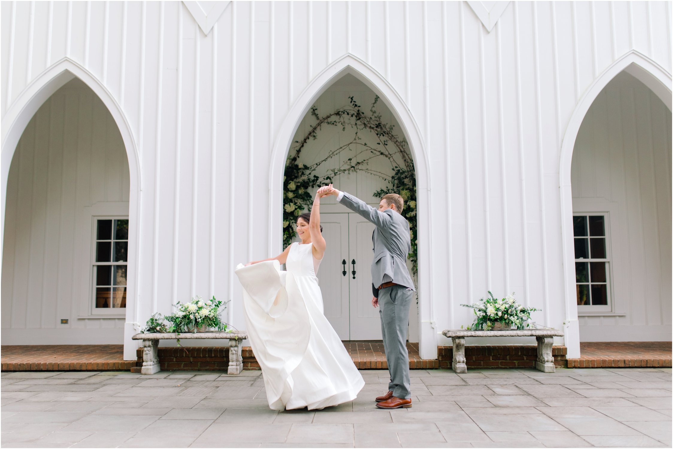 Groom twirls bride in front of a church
