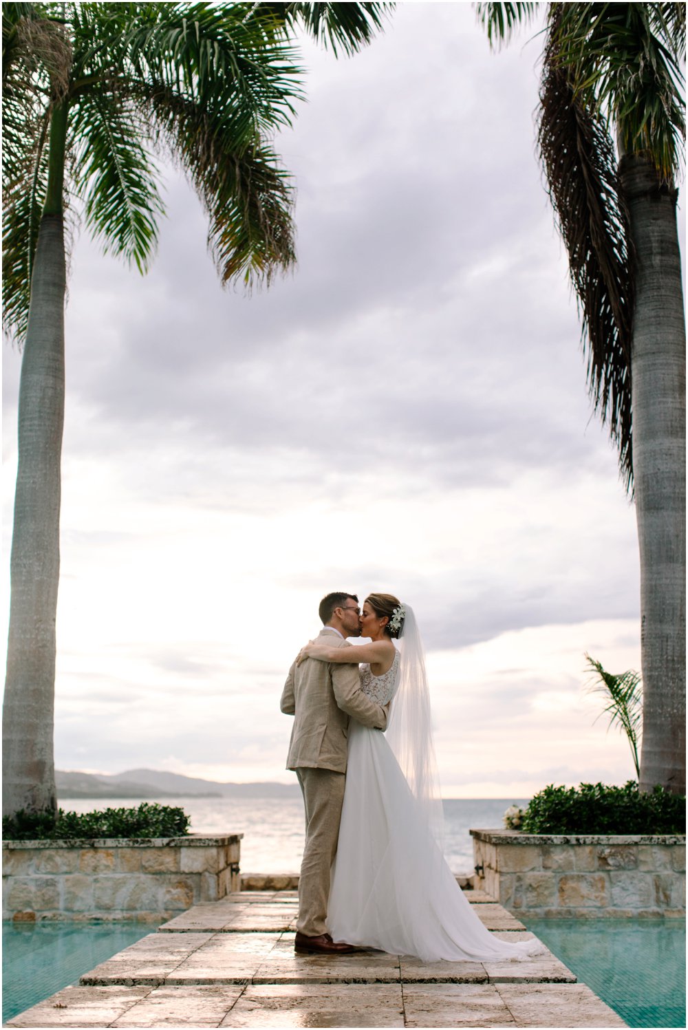 Caribbean wedding couple kisses between palm trees