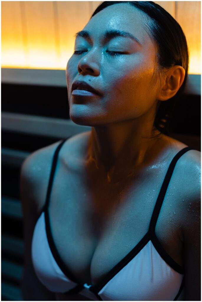 Women in red light therapy sauna at Purify in Richmond, Va. Her eyes are clothes and she is enjoying the benefits of the sauna.