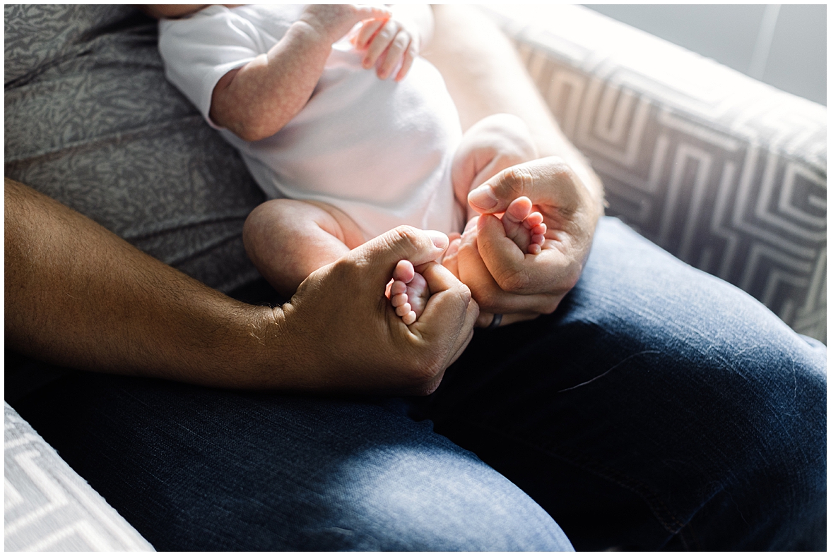 Dad Holds Newborn, Baby Feet Cozy in Father's Hands