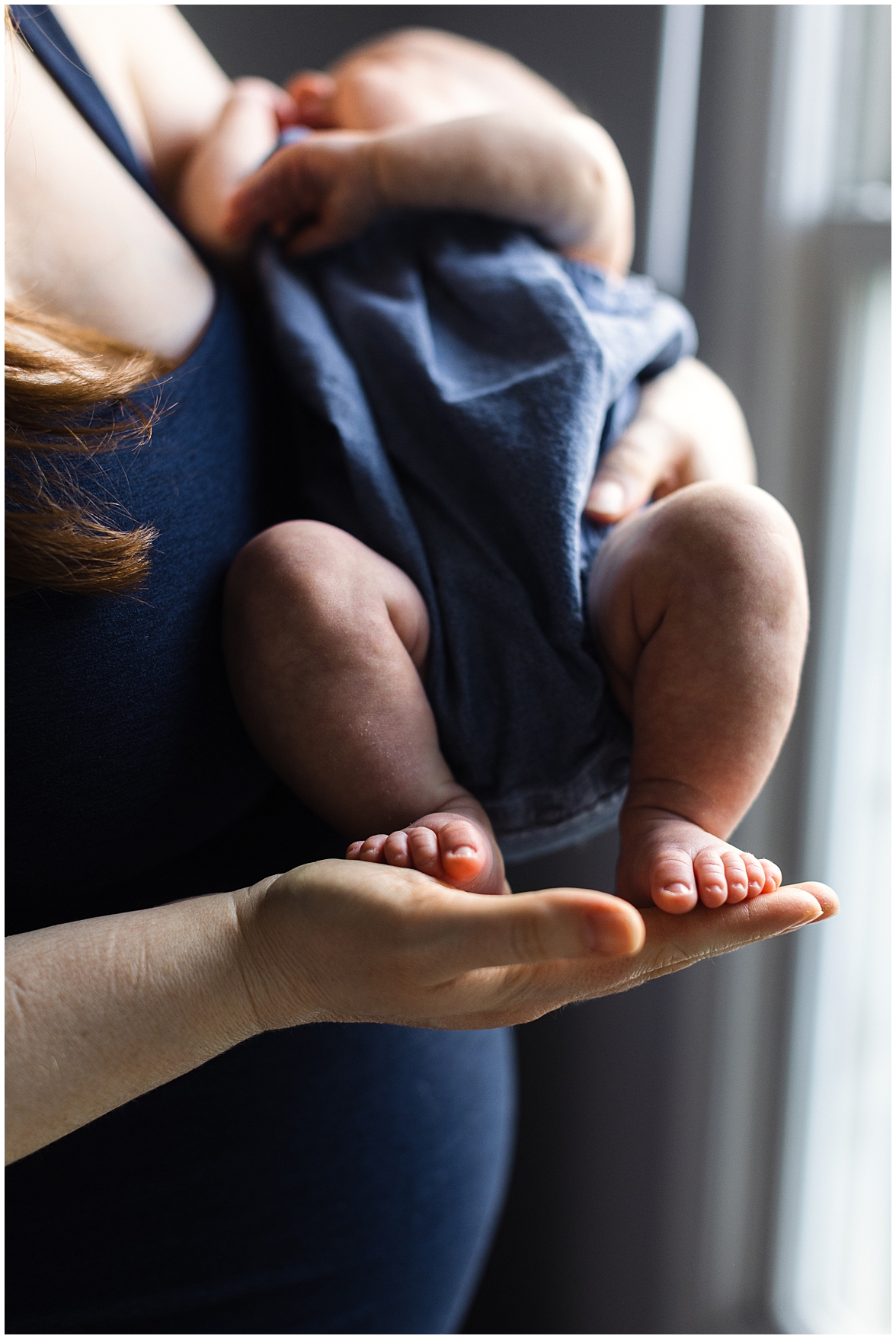 Newborn photography of a moms hands holding baby feet