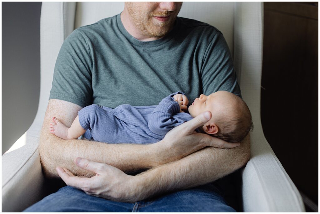 This is a picture of a dad helping out with the newborn baby because his wife is transitioning into becoming a mother of two. 