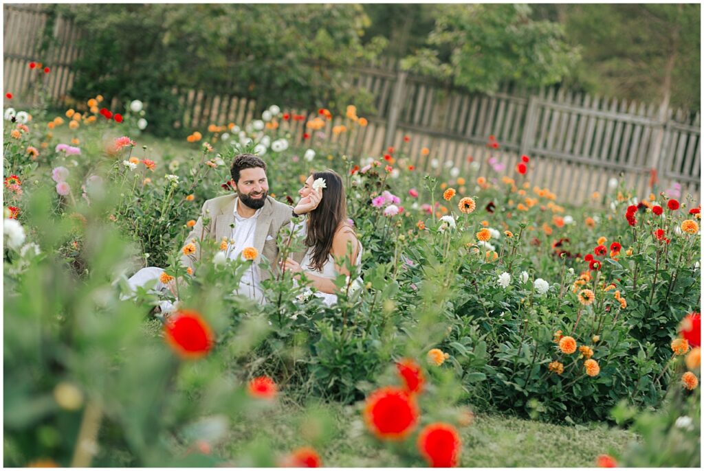 Preserve at Dundee engagement with couple playing in flower bed. Guy puts flower behind girls ear.
