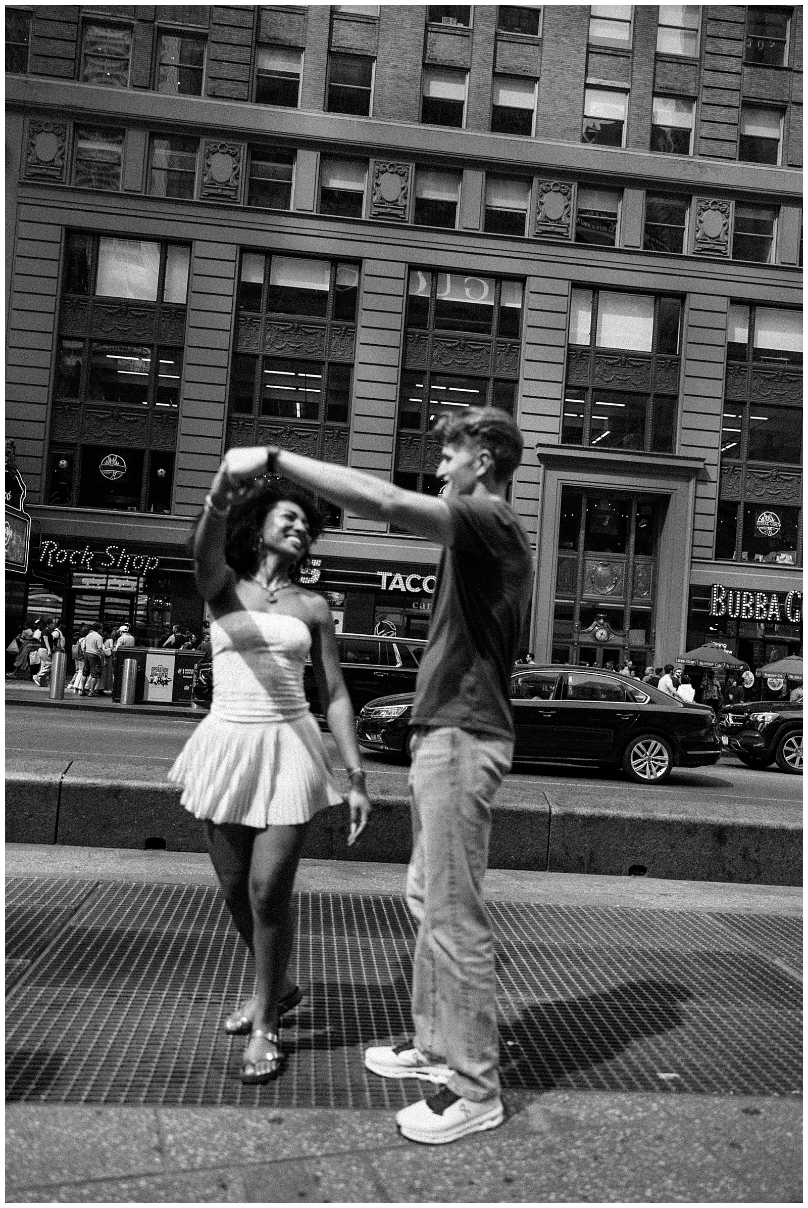 Black and White Photo of Couple Dancing, Doing a twirl in Front of Brick Building in New York