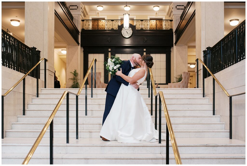 Bride and Groom Kiss on Marble Stairway of The John Marshall Ballrooms