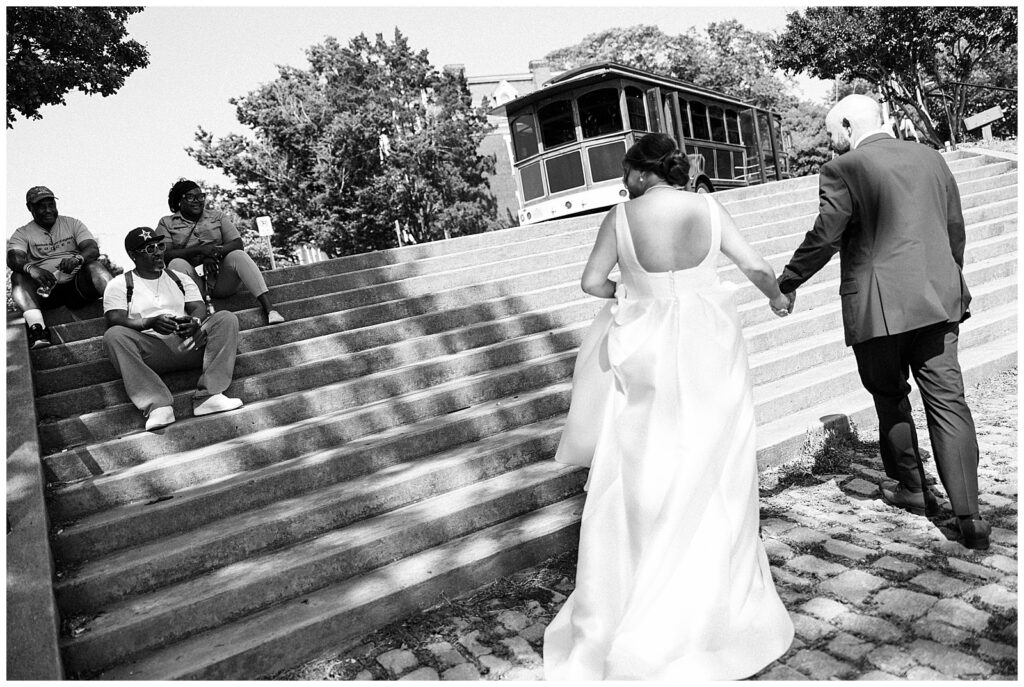 Bride and Groom Hold Hands, Walk Through Park on Day of Wedding