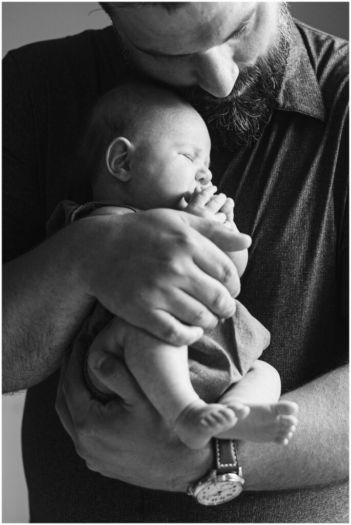 Newborn photography of a black and white picture of a dad snuggling with his newborn daughter. 